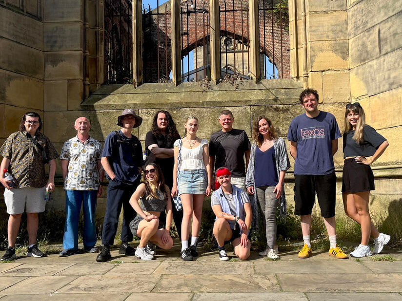 A large group of people outside a church ruin, playing a treasure hunt