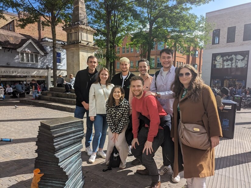 A group of colleagues enjoying a treasure hunt, stood in the sunshine.