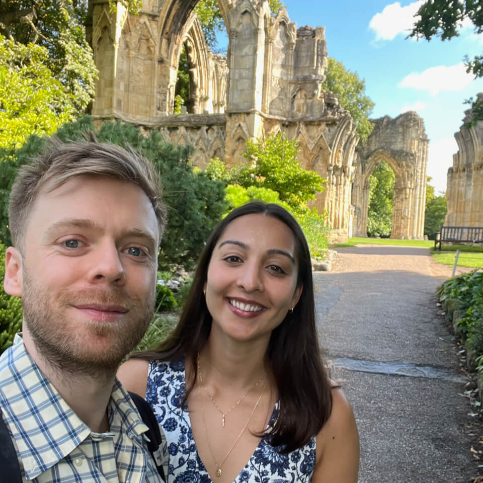 Couple exploring historic abbey ruins on a sunny day during a UK city treasure hunt tour.
