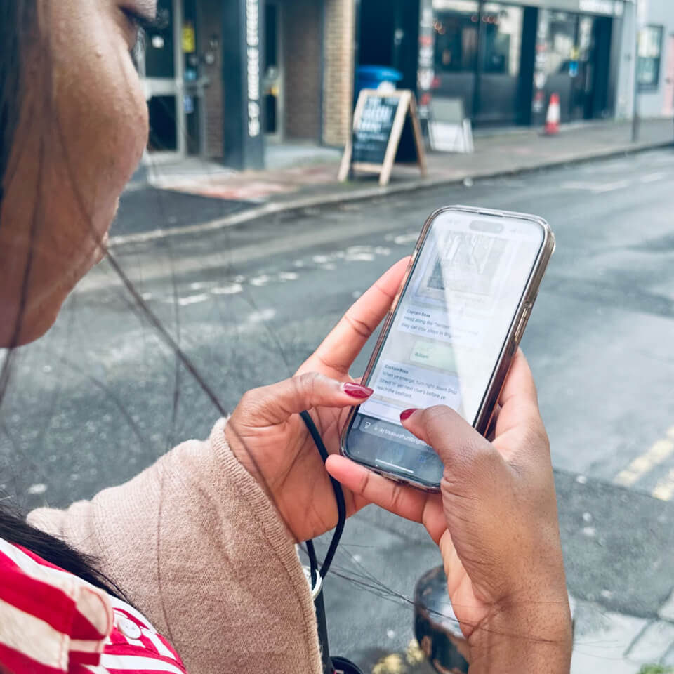 Woman checking puzzle clues on her smartphone while navigating streets on a treasure hunt tour.